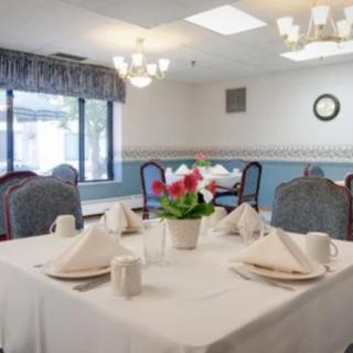A neatly set dining table in a well-lit restaurant with floral centerpiece.