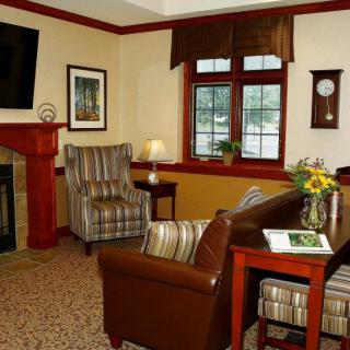 Cozy living room with a fireplace, armchairs, and a coffee table near a window.