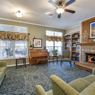 A cozy living room featuring a piano, fireplace, and bookshelves with comfortable seating.