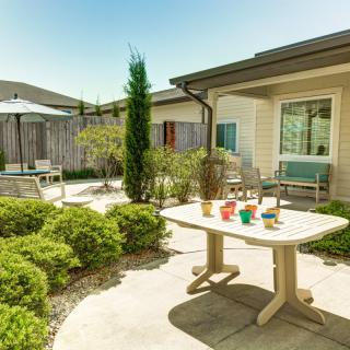 A sunny patio with a table, chairs, and well-maintained garden.
