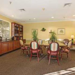 A cozy conference room with a large table, chairs, and bookshelves.