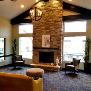 A modern living room with a stone fireplace, vaulted ceiling, and large windows.
