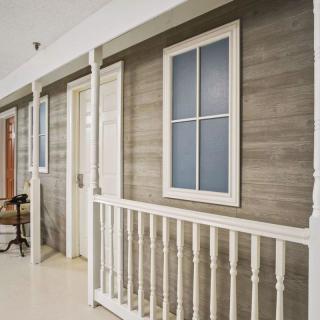 A wooden porch with white railings and windows.