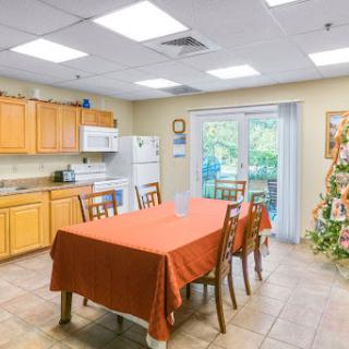 A cozy kitchen and dining area featuring a wooden table with an orange tablecloth, surrounded by chairs, and equipped with modern kitchen appliances.