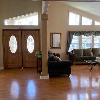 A well-lit living room with hardwood floors, sofas, and large windows.