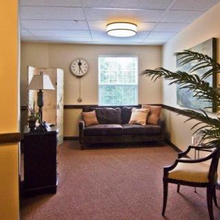 A cozy waiting room with a sofa, chair, and decorative elements.