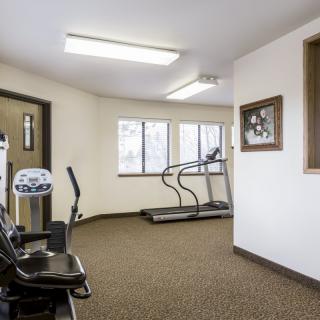 A small gym with exercise equipment including a treadmill and elliptical machine.