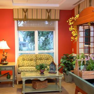 A cozy living room with warm red walls, a patterned sofa, and various plants enhancing the decor.