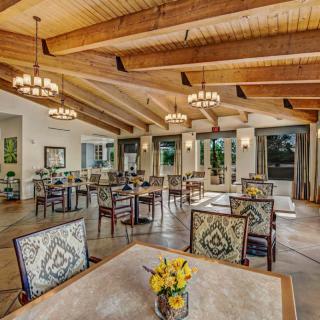 A spacious dining room with wooden beams, elegant chandeliers, and beautifully decorated tables.