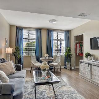 A cozy and elegantly furnished living room with a small dining area near large windows.