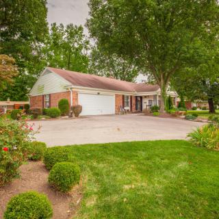 A suburban house with a garage and well-maintained lawn surrounded by trees.