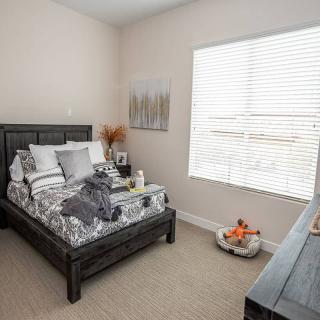 A cozy, minimalist bedroom with a neatly made bed and a large window.