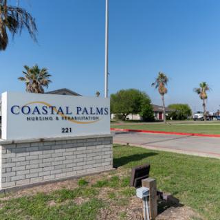 The Coastal Palms establishment, surrounded by palm trees and clear blue skies.