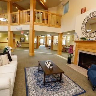 A spacious and warmly decorated living room with a cozy fireplace, comfortable seating, and a wooden balcony overhead.