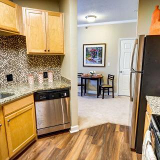 A modern kitchen with stainless steel appliances, wooden cabinetry, and a granite countertop leading to a cozy dining area.