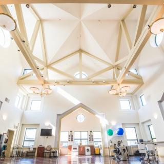 A spacious rehabilitation gym with high ceilings and exercise equipment.