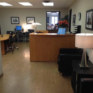 A view of a modern office reception area with desks, seating, and decorative elements.