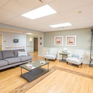 A cozy and inviting living room space featuring a sofa, armchairs, and a coffee table, illuminated by natural light.