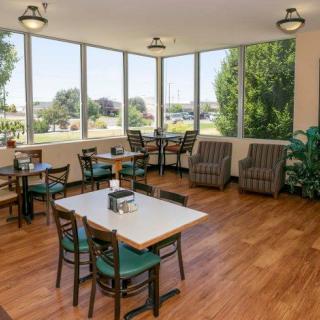 A cozy dining area with tables and chairs, featuring large windows overlooking the outdoors.