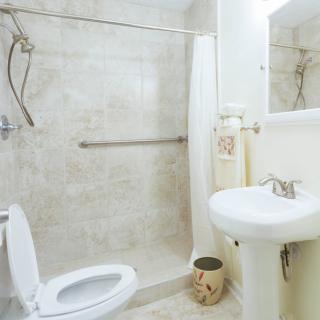 A clean bathroom with a toilet, sink, and shower area.