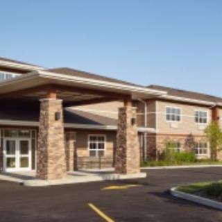 A modern building with a stone facade and large entrance, set against a clear blue sky.