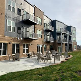 A view of a modern apartment complex featuring multiple balconies and outdoor seating areas.