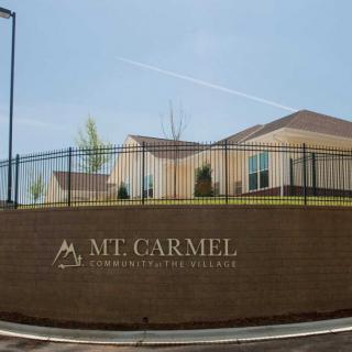 A brick wall with a sign for Mt. Carmel Community Services in front of a residential building.