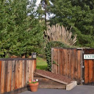 A wooden gate marks the entrance to a garden surrounded by lush greenery.