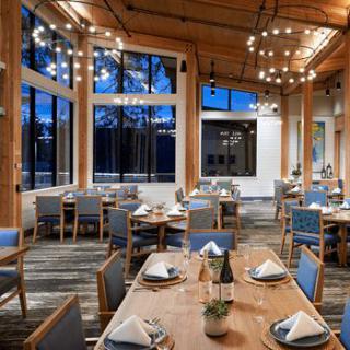 An elegant restaurant dining room with neatly set tables and large windows.