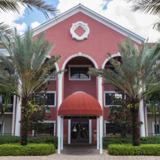 A vibrant commercial building with a red facade and palm trees framing the entrance.