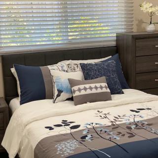 A neatly made bed with decorative pillows and a floral patterned blanket in a well-decorated bedroom.