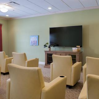A seating area with multiple chairs facing a large television.