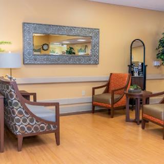 A cozy lounge area featuring comfortable chairs, a decorative mirror, and warm lighting.