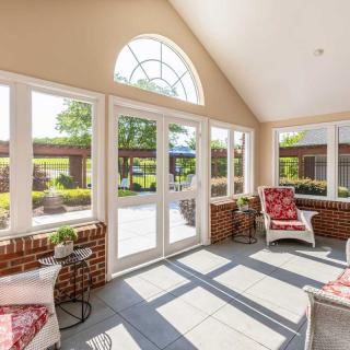 A bright sunroom with large windows and comfortable seating, offering a view of the garden outside.