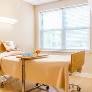A clean and organized hospital room with a single patient bed and large windows.