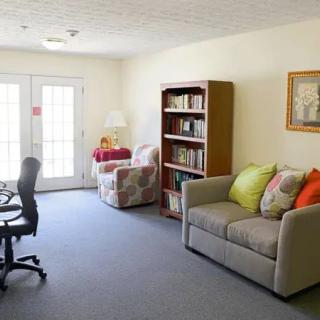 A cozy living room with a sofa, bookshelf, and desk chair.