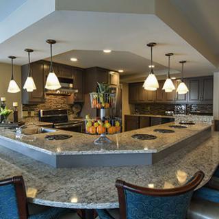 A modern kitchen with granite countertops, pendant lights, and bar seating.