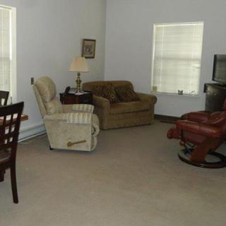 A cozy living room with various furniture pieces including sofas, chairs, a lamp, and a television.