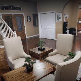 A cozy living room with four chairs and a wooden table decorated with small plants.