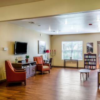 A cozy living room with comfortable chairs, a television, and a wooden floor.