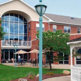 A modern brick building with arched windows, surrounded by a green lawn and outdoor seating areas.