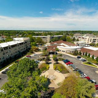 Aerial view of a modern complex featuring landscaped areas, parking spaces, and surrounding greenery.