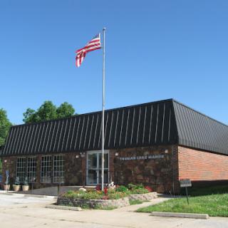 A brick building with a black roof and an American flag flying in front under a clear blue sky.