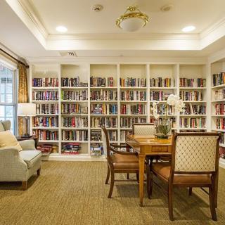 A cozy library room with bookshelves, a reading table, and comfortable seating.
