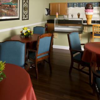 A cozy cafe interior with tables and chairs, featuring decorative flowers and ice cream-themed decor.