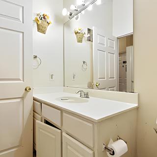 A clean and bright bathroom with a sink, mirror, and cabinets.