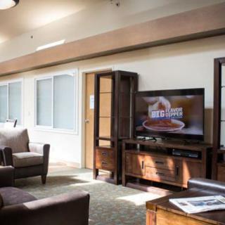 A cozy living room featuring a sofa, armchair, and a television set.