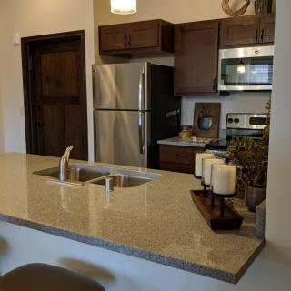 A modern kitchen with stainless steel appliances and a spacious countertop featuring decorative candles.