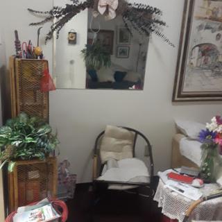 A cozy corner featuring a seating area with decorative plants, a mirror, and artwork.