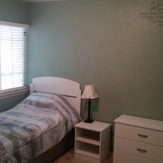A minimalist bedroom with a single bed, nightstand, and dresser.